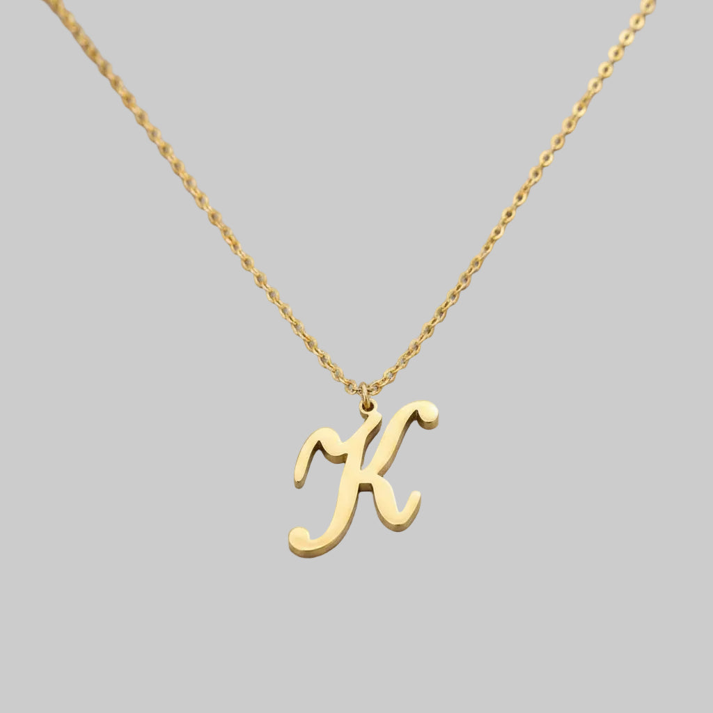 Gold necklace with a 'K' pendant on a gray box